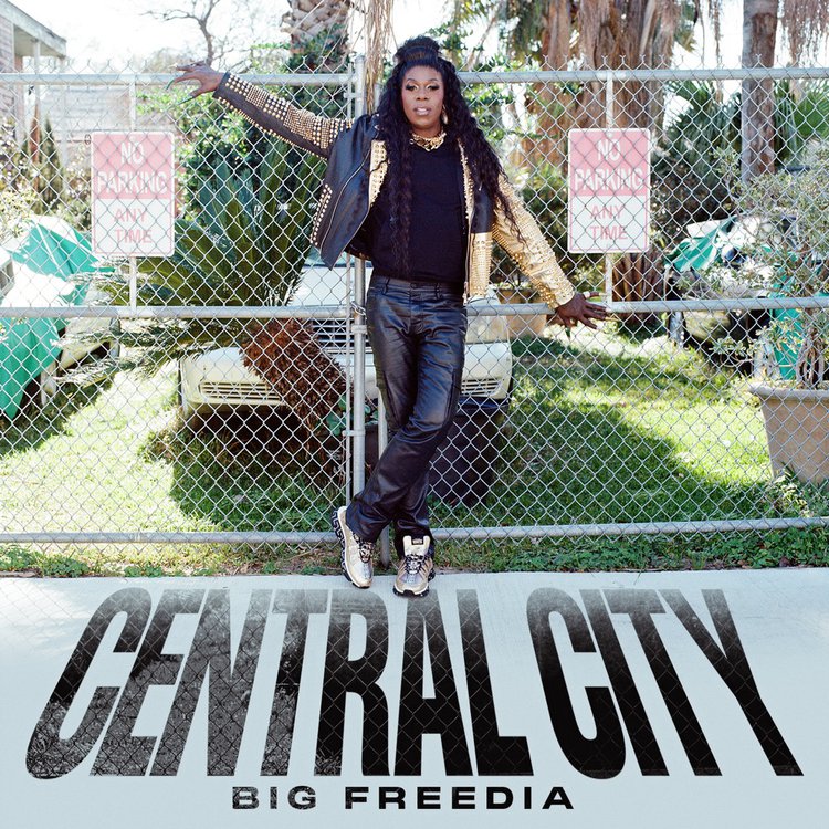 Big Freedia standing leaning on a chainlink fence.